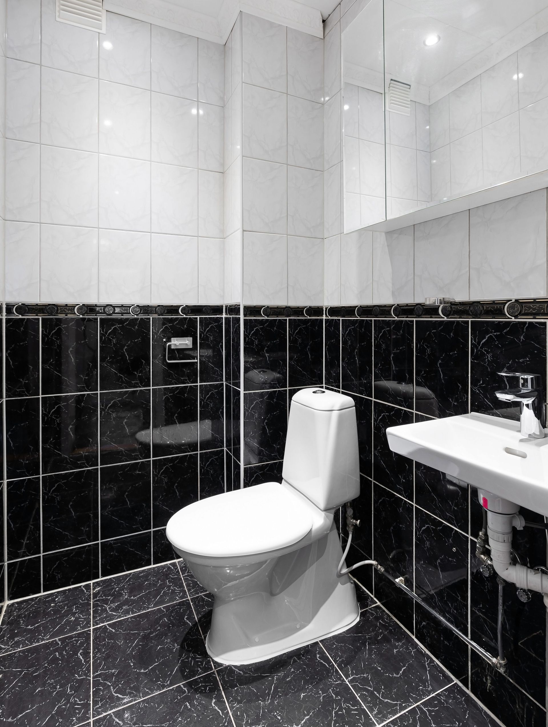 Sleek and modern bathroom with black and white tiles and fixtures.